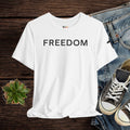 White t-shirt with 'FREEDOM' text on a wooden surface with jeans and sneakers.