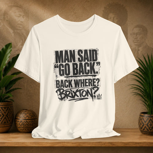 Beige t-shirt with black text on a wooden shelf with plants and a brown background