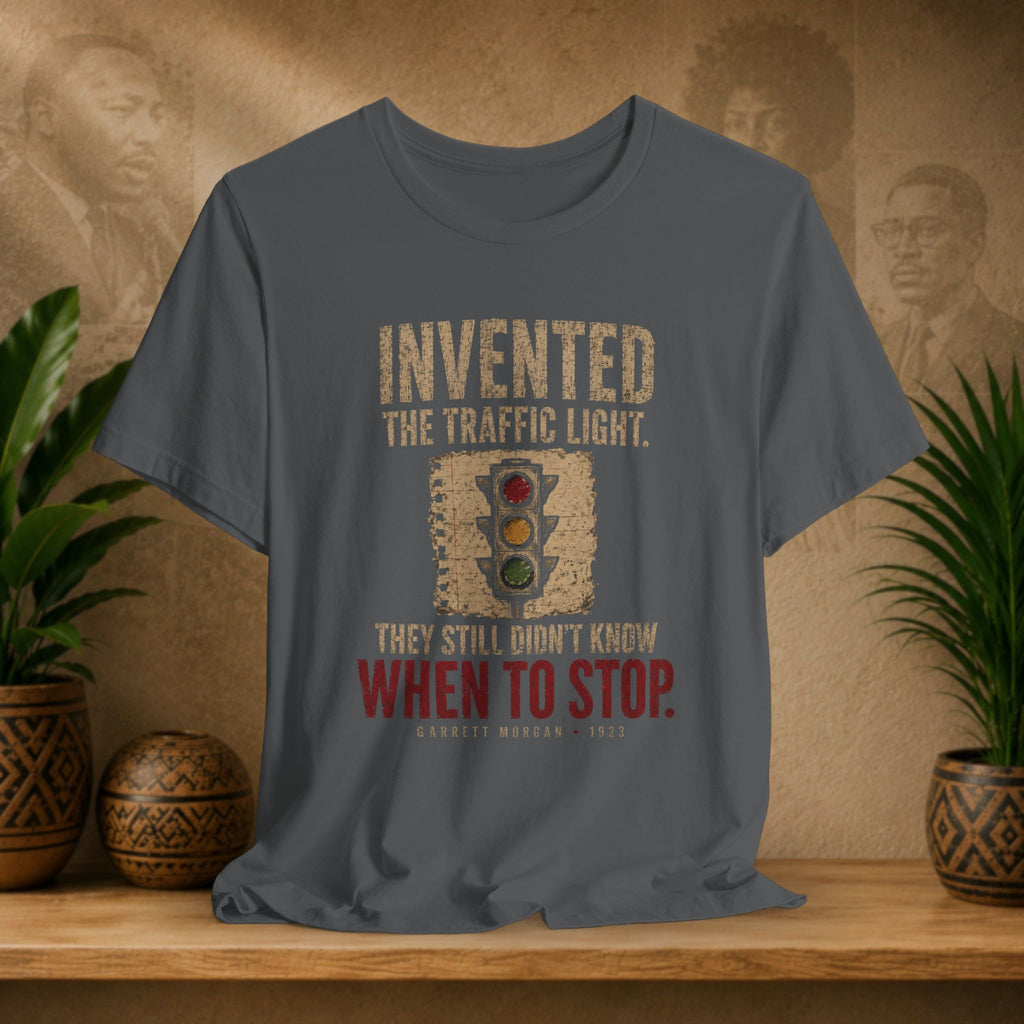 Gray t-shirt with a graphic and text on a wooden surface with plants and decorative items.