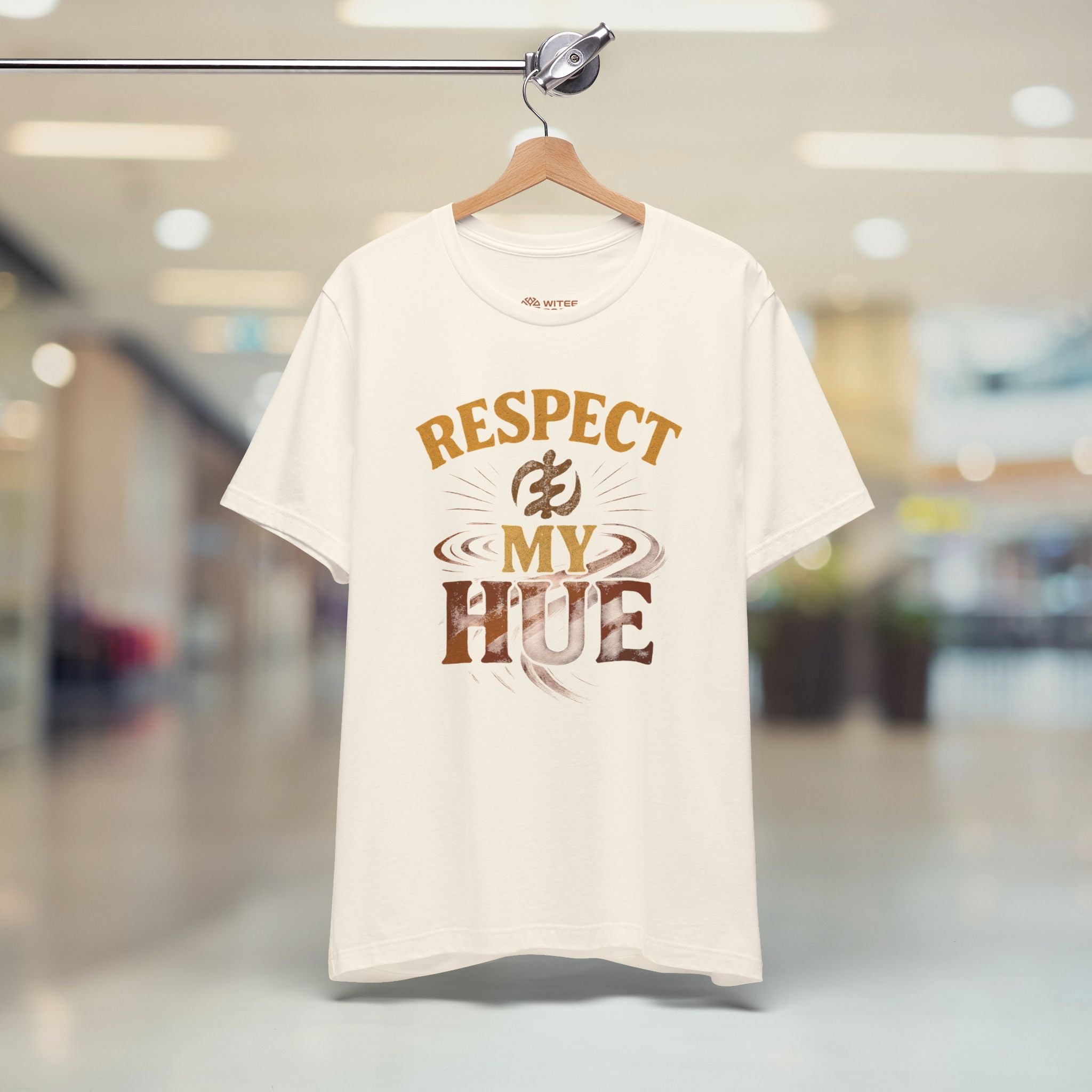 Cream t-shirt with 'RESPECT MY HUE' text on a hanger in a store setting