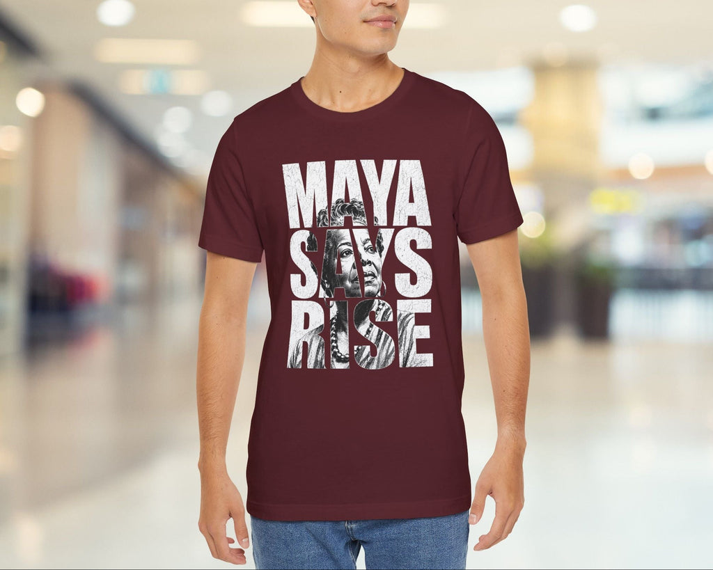 Man wearing a maroon t-shirt with graphic design and text in a blurred indoor setting