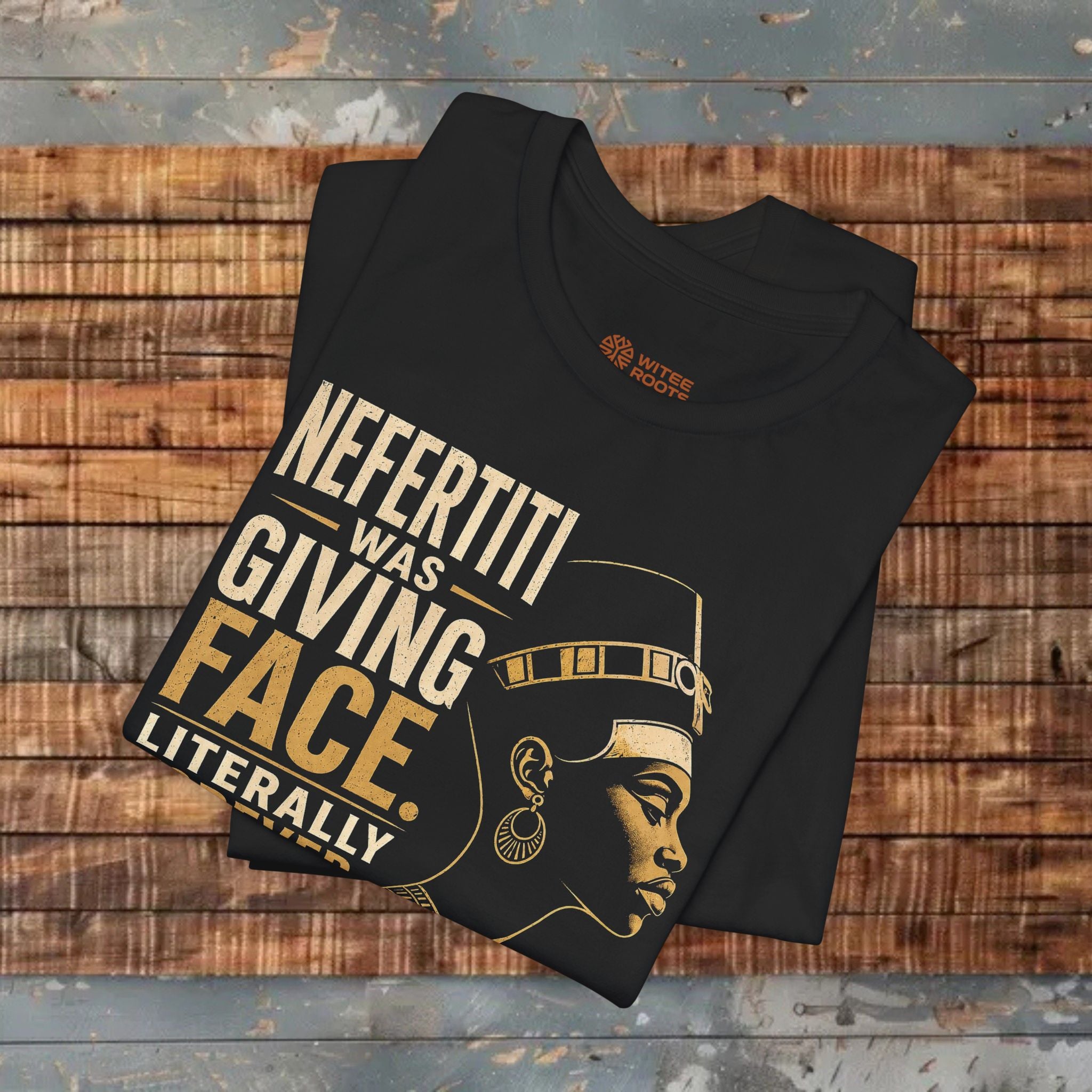 Black t-shirt with gold text and graphic of a woman on a wooden surface