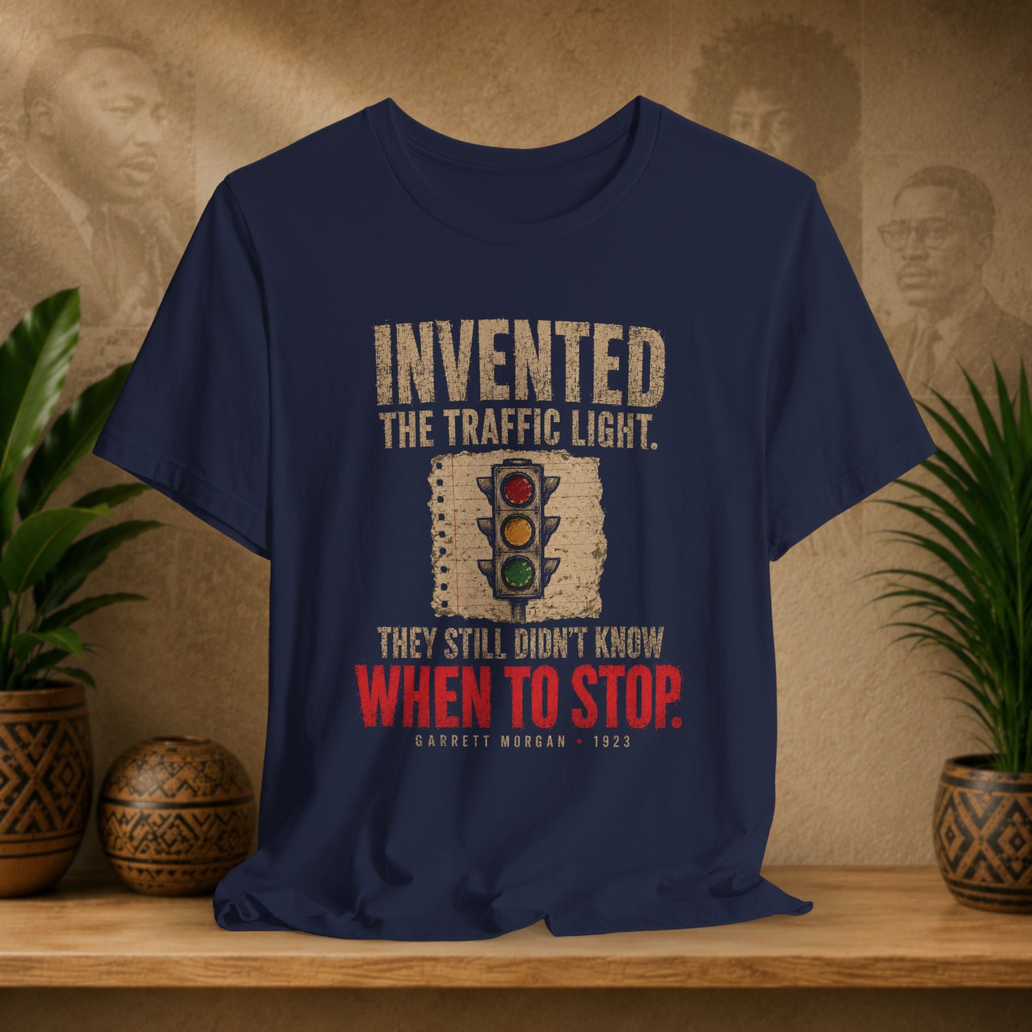 Navy t-shirt with traffic light graphic and text on a wooden surface with plants and decorative items.