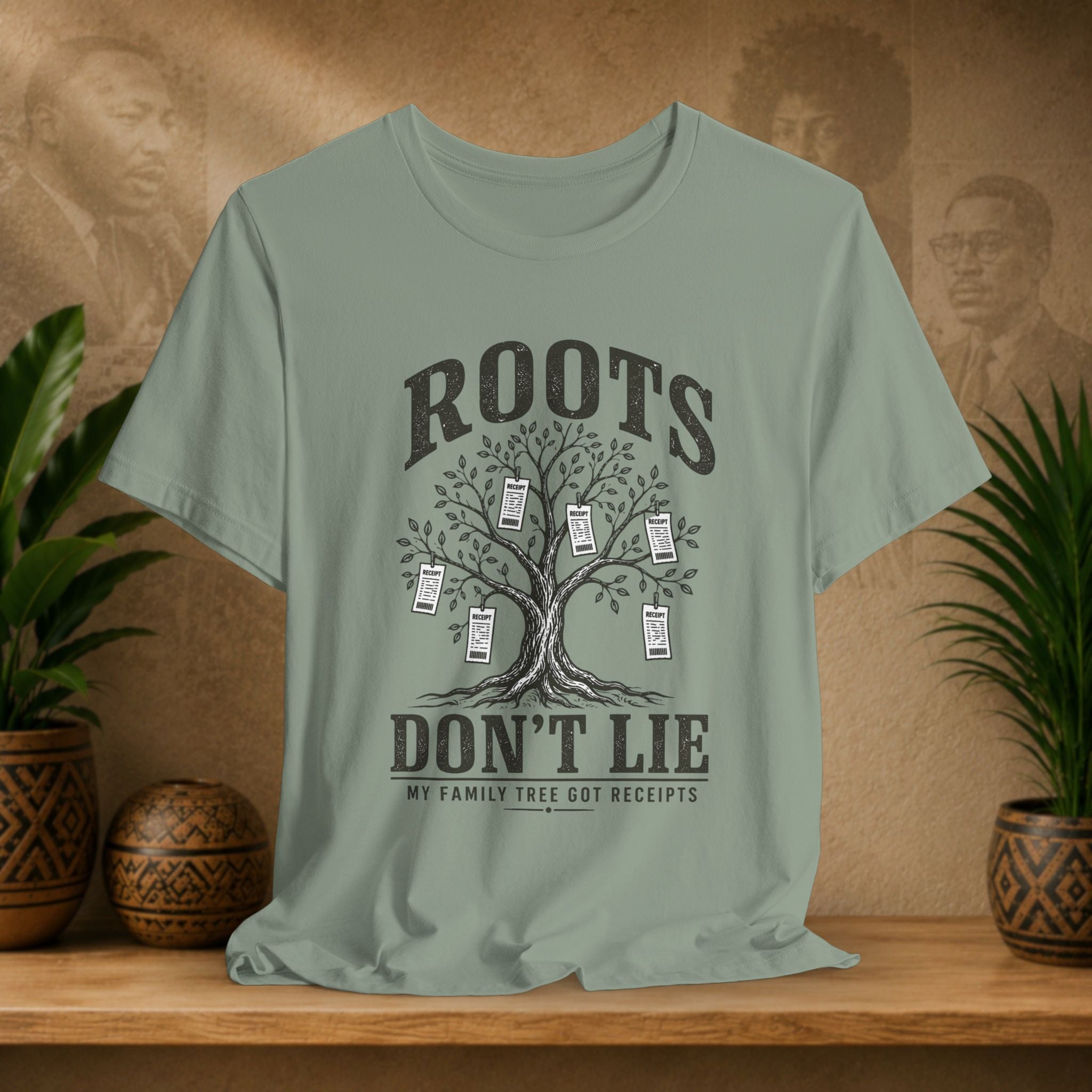 Light green t-shirt with family tree graphic and text on a wooden surface with plants and a textured wall background.