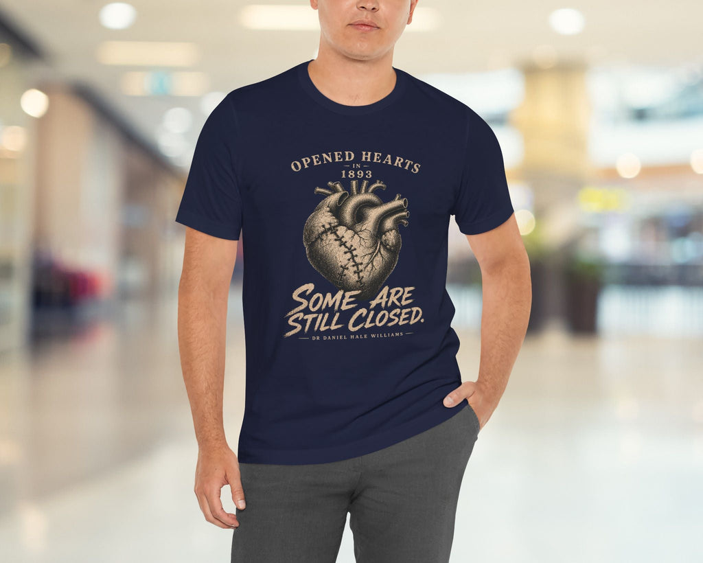 Man wearing a navy blue t-shirt with a heart graphic and text in a blurred indoor setting