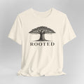 Beige t-shirt with a tree graphic and 'ROOTED' text on a gray background