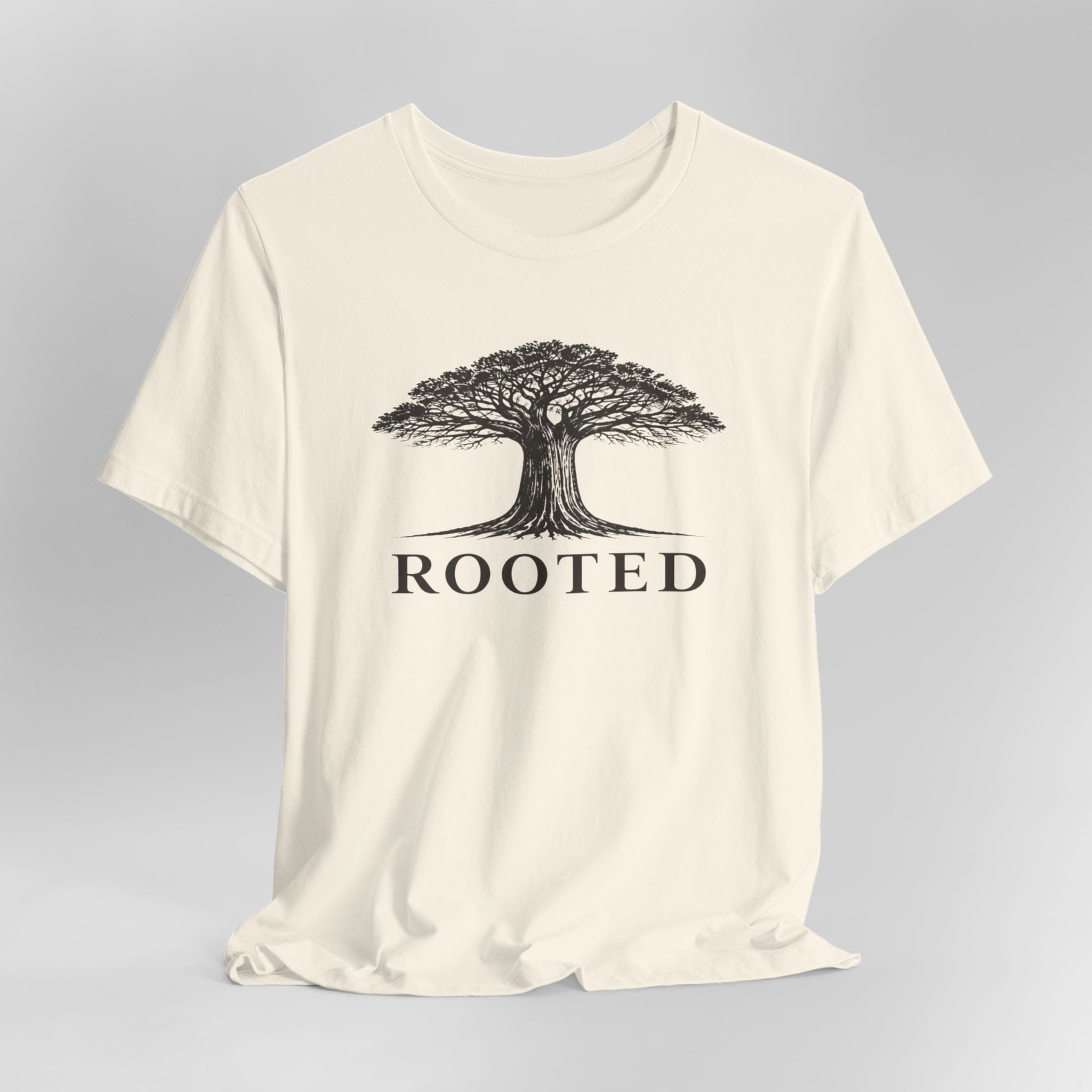 Beige t-shirt with a tree graphic and 'ROOTED' text on a gray background