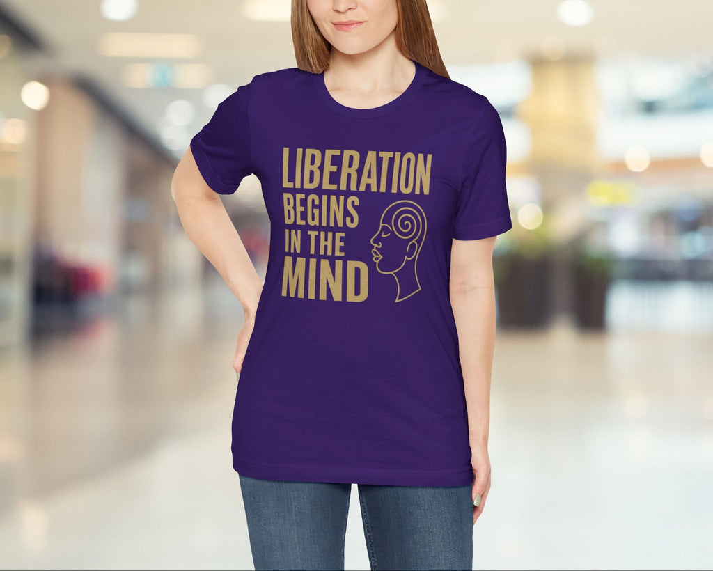 Woman wearing a purple t-shirt with text and graphic in a blurred indoor setting
