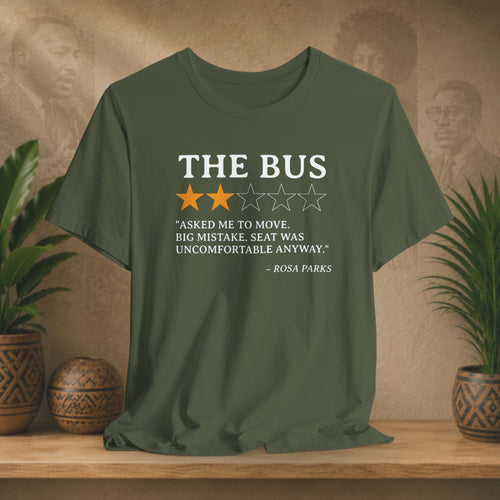 Green t-shirt with a quote on it displayed on a wooden surface with plants and a wall in the background.