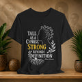 Black t-shirt with motivational quote on a wooden surface with plants and decorative items.
