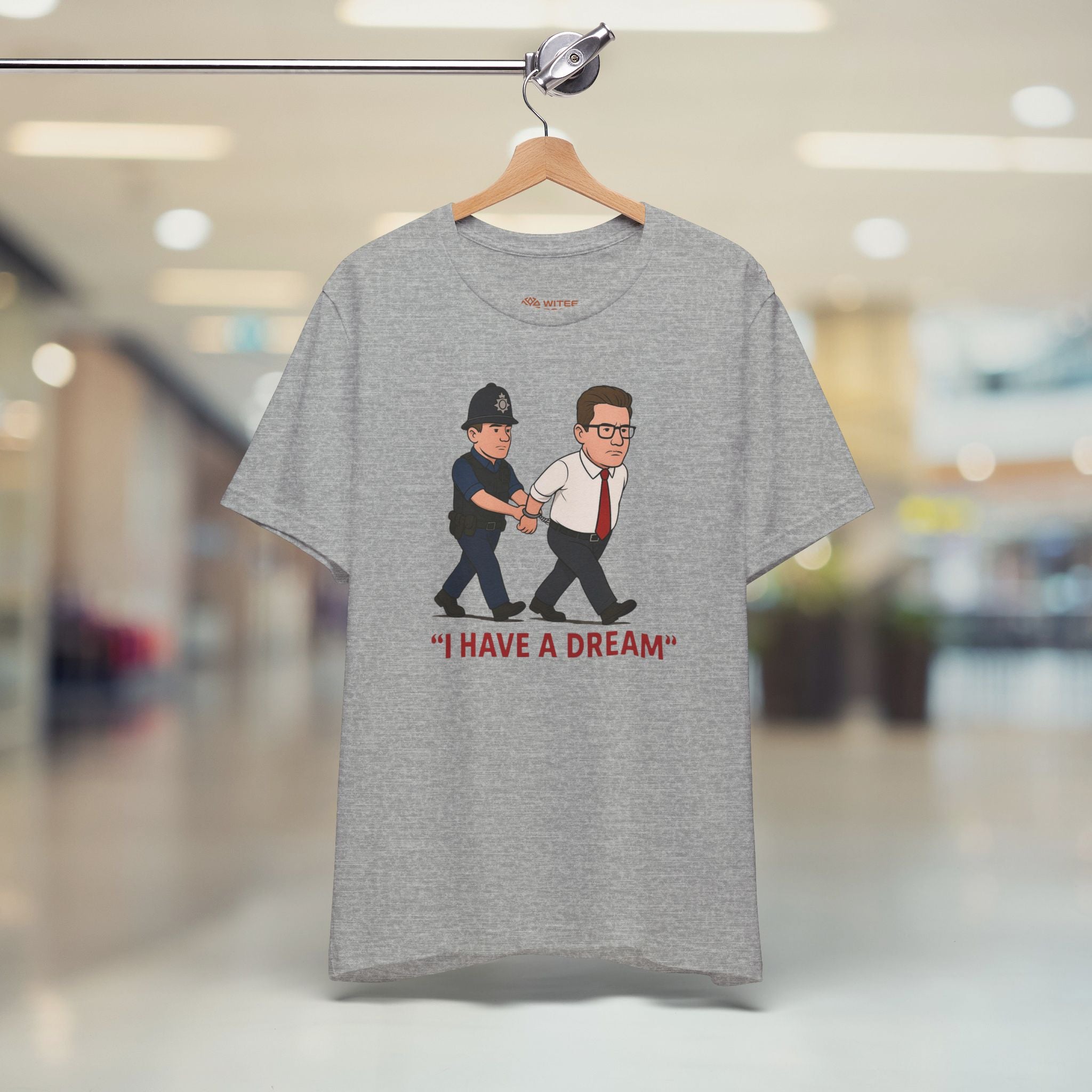Gray t-shirt with graphic design of two men being arrested and 'I HAVE A DREAM' text, hanging in a store.