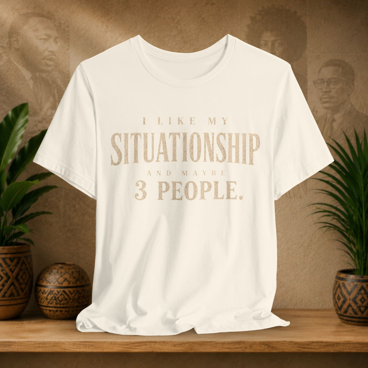 Off-White t-shirt with humorous text design on a wooden surface with plants and a textured wall background