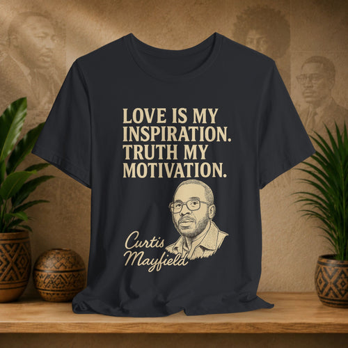 Black t-shirt with text and portrait of Curtis Mayfield on a wooden surface with plants and wall art.