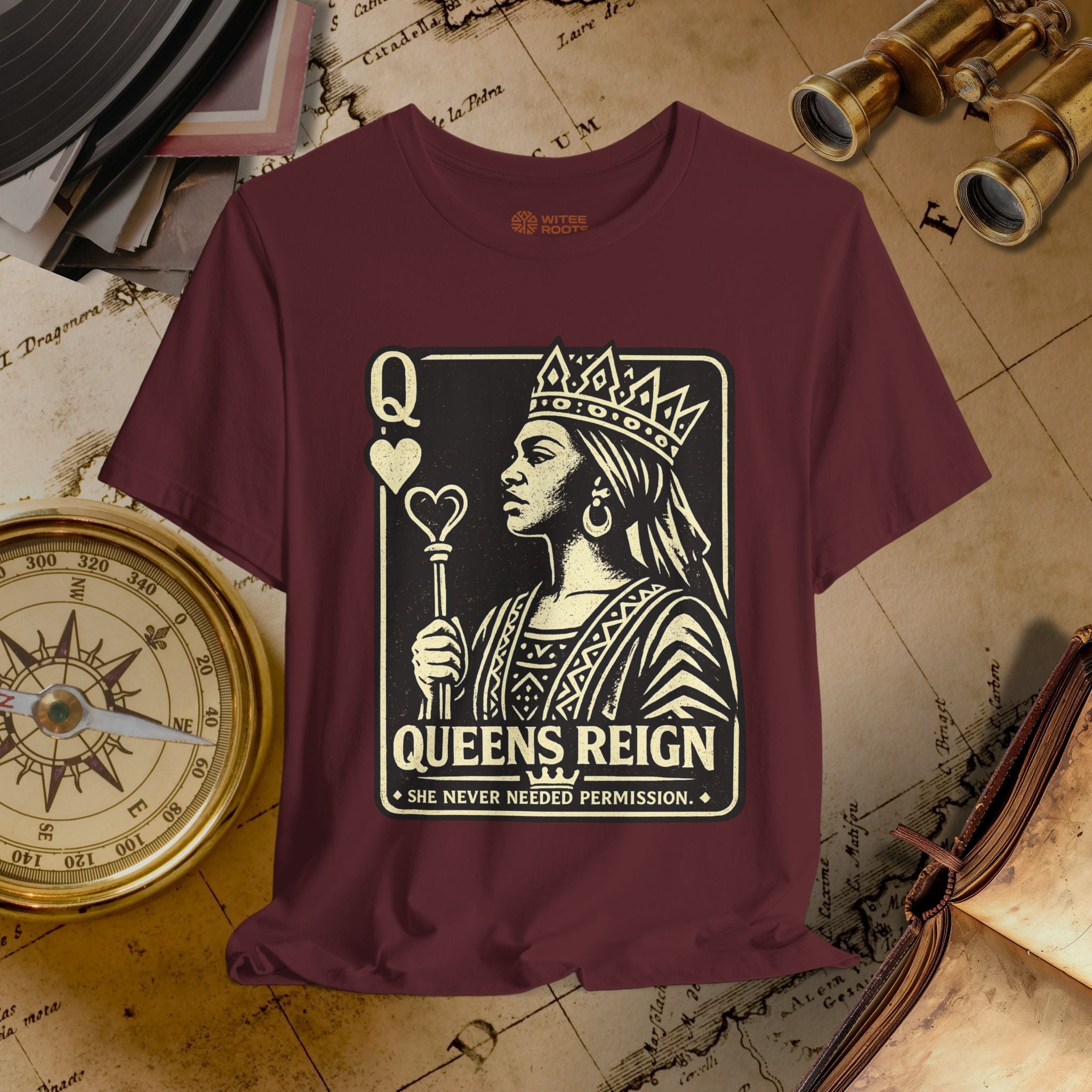 Maroon t-shirt with a graphic design of a queen and text 'Queens Reign' on a vintage map background.