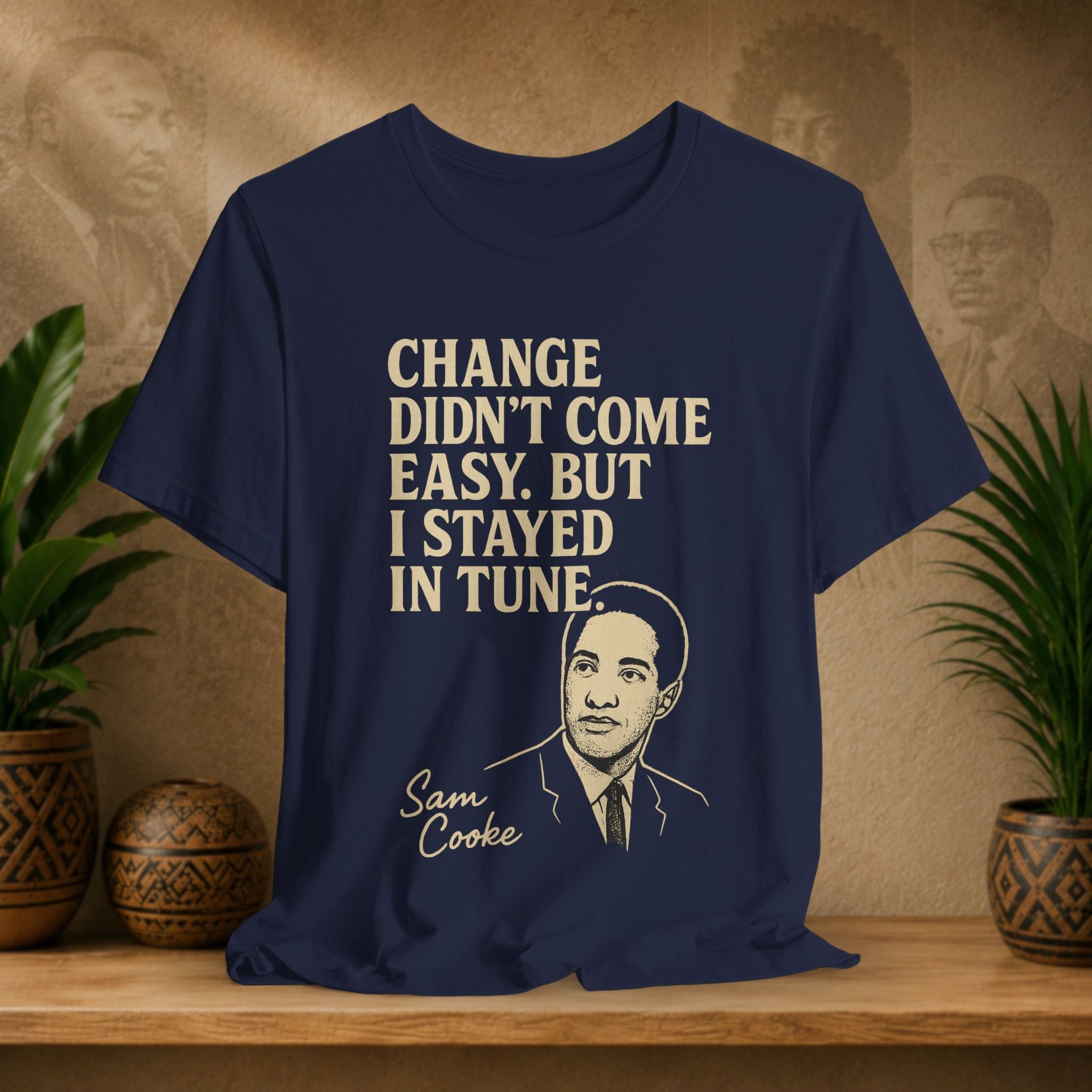 Navy blue t-shirt with text and a portrait on a wooden surface with plants and a wall in the background