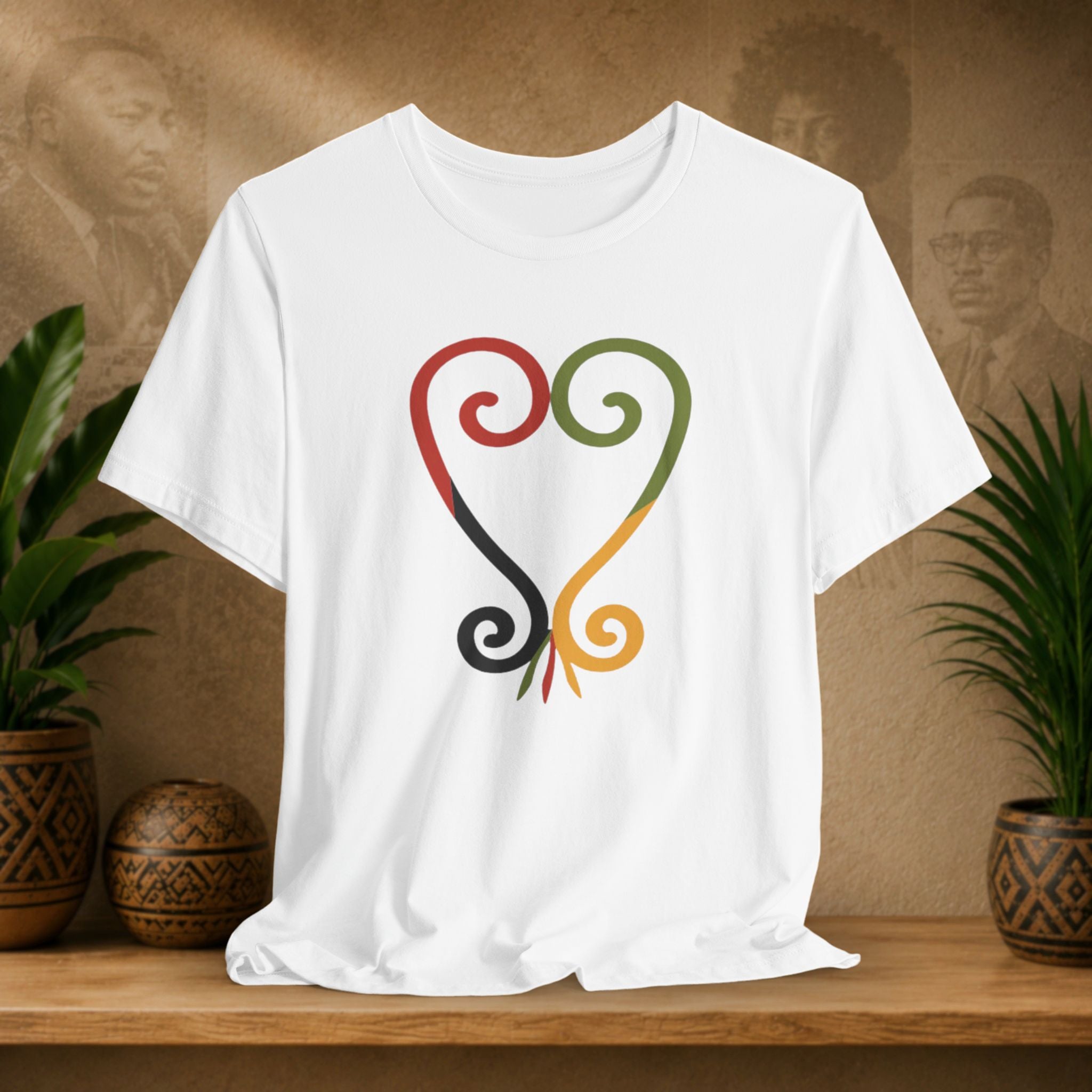 White t-shirt with a colorful design on a wooden surface with plants and a textured wall background