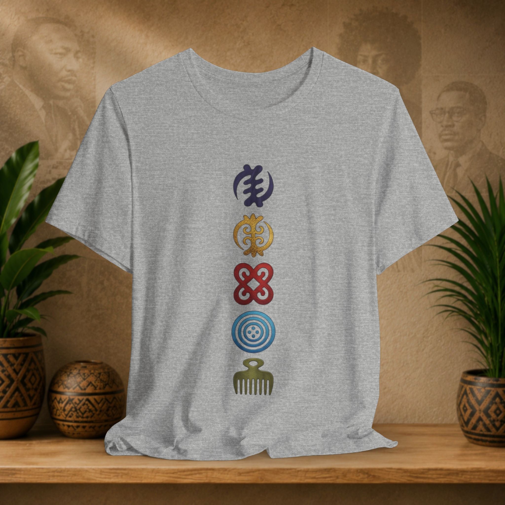 Gray t-shirt with colorful symbols on a wooden shelf with plants and decorative items.