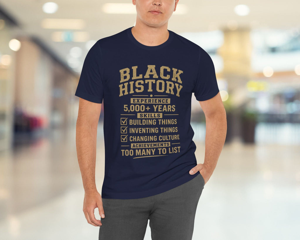 Man wearing a navy blue t-shirt with 'Black History' text in a modern indoor setting