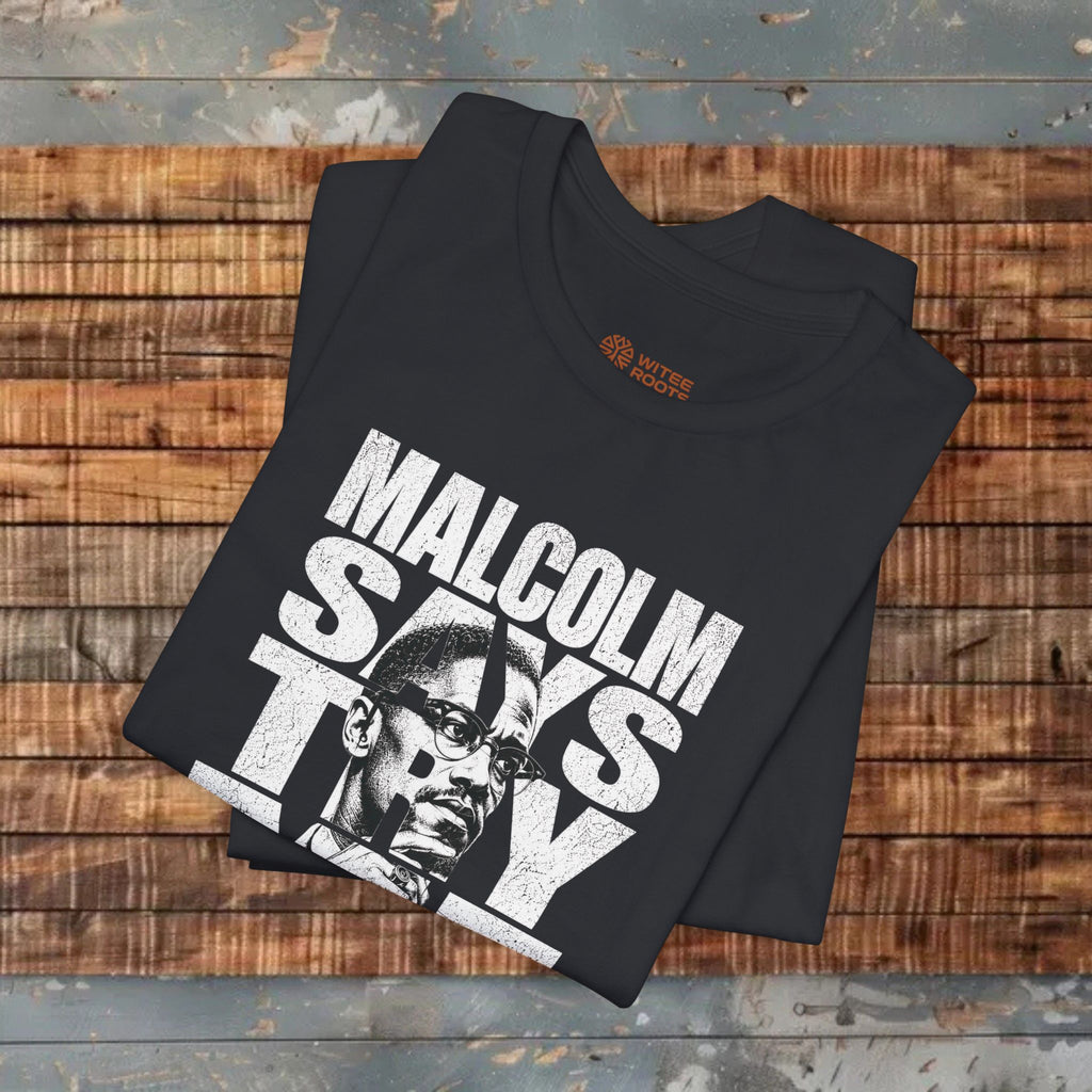 Black t-shirt with 'Malcolm Says Ty' design on a wooden surface