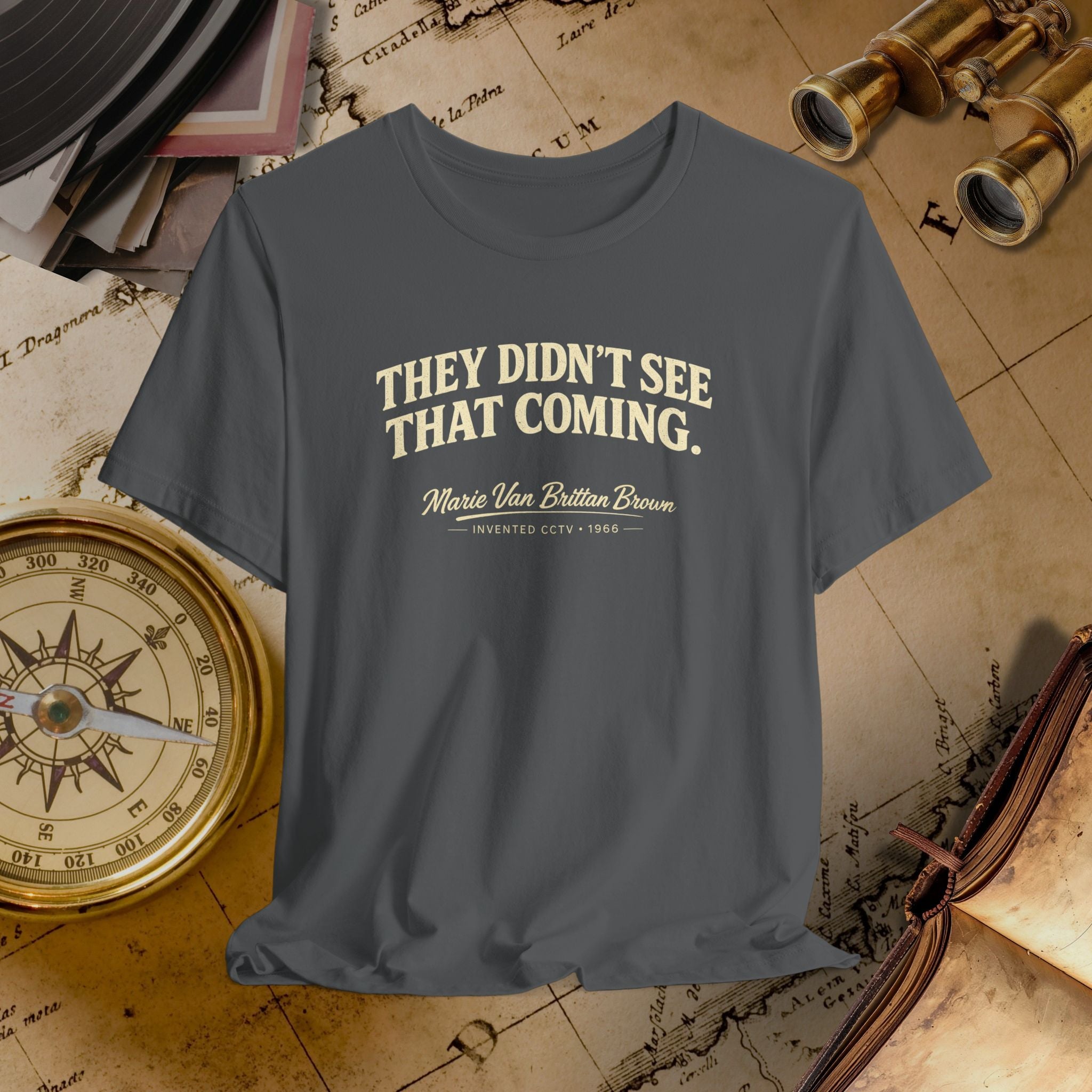 Gray t-shirt with 'They Didn't See That Coming' text on a vintage map background