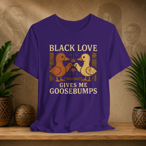 Purple t-shirt with 'Black Love Gives Me Goosebumps' graphic on a wooden surface with plants in the background