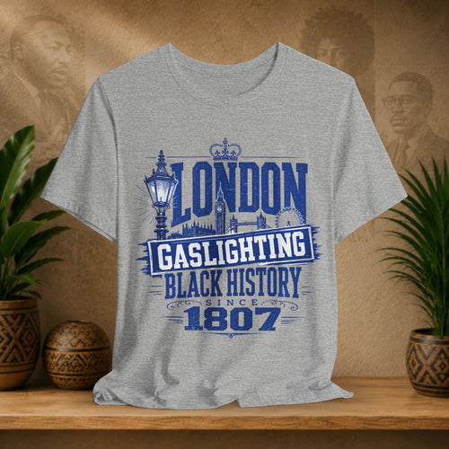 Gray t-shirt with blue text and graphics on a wooden surface with plants and a blurred background