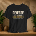 Black t-shirt with 'Diverse by Design' text on a wooden surface with decorative items in the background