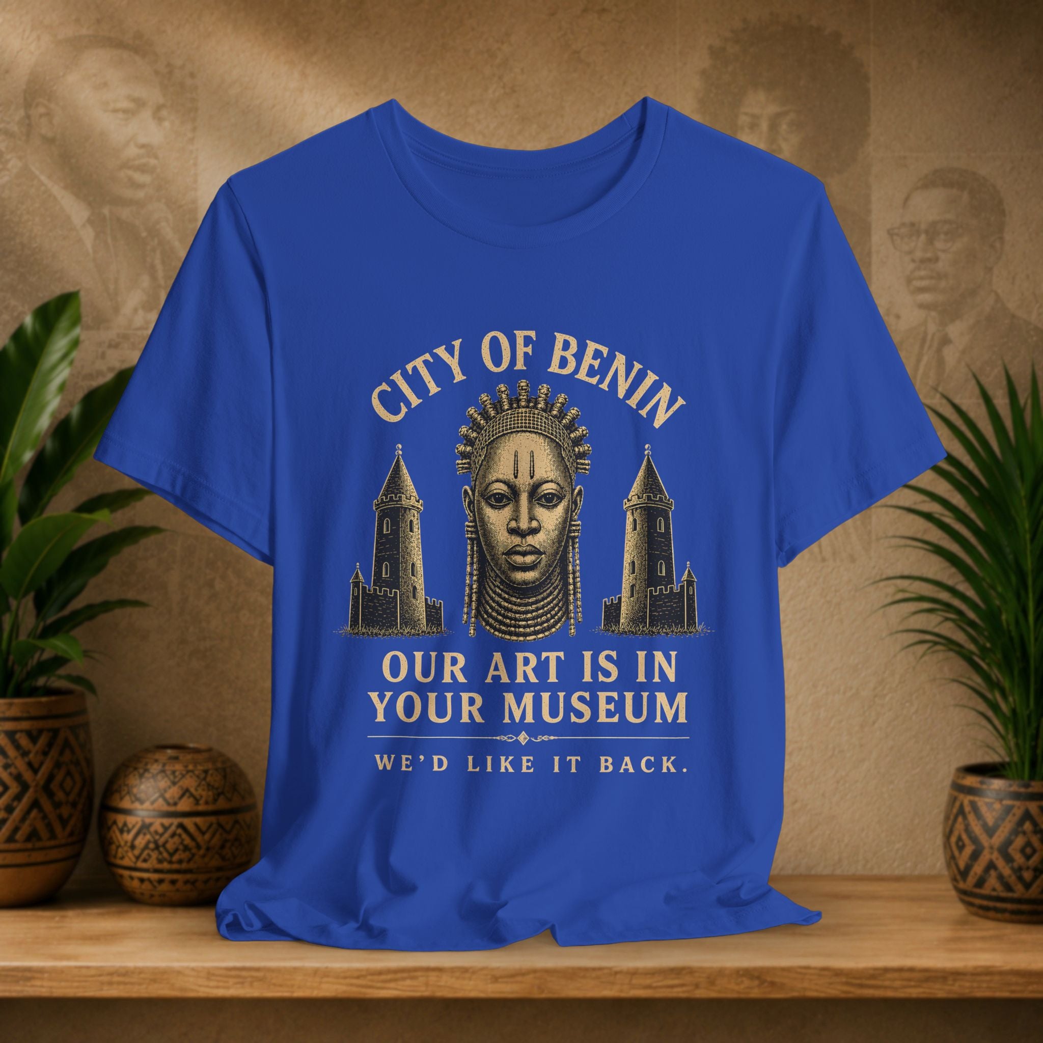 Blue t-shirt with a graphic design and text on a wooden surface with plants and decorative items.