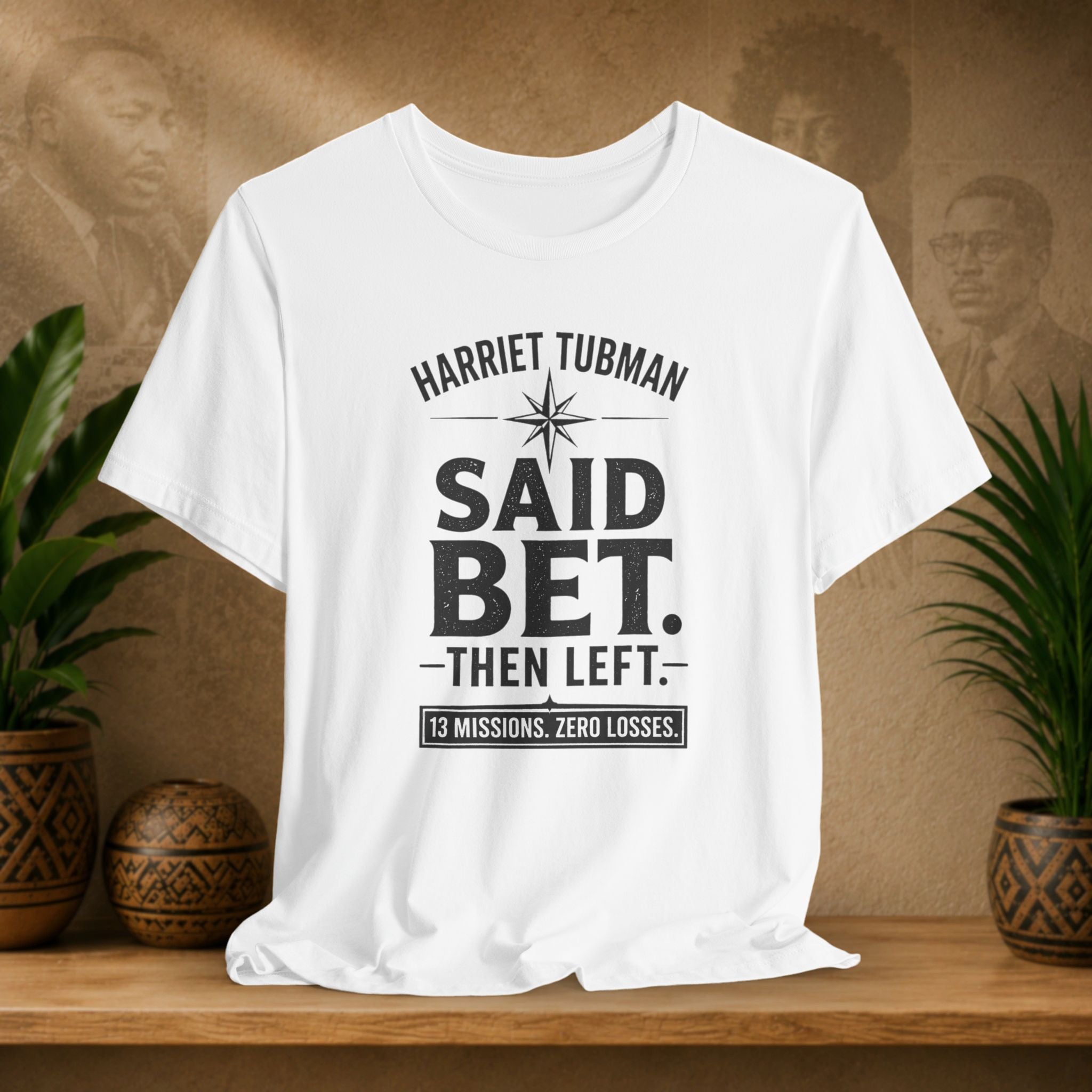 White t-shirt with text on a wooden surface with plants and a decorative item in the background