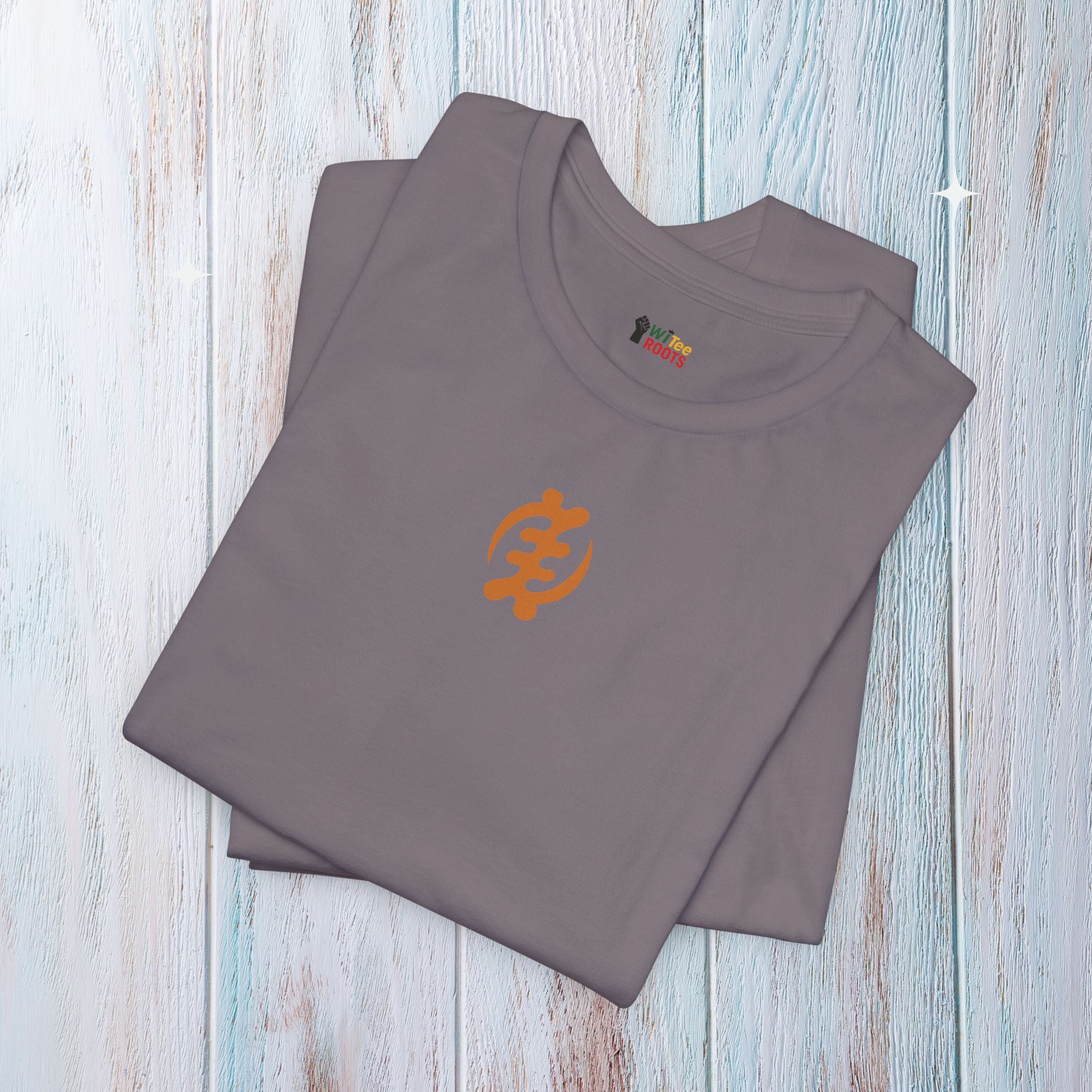 Folded gray t-shirt with orange logo on a light wooden surface