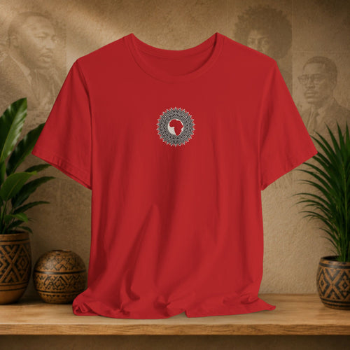 Red t-shirt with a circular design on a wooden surface with plants and a textured wall in the background