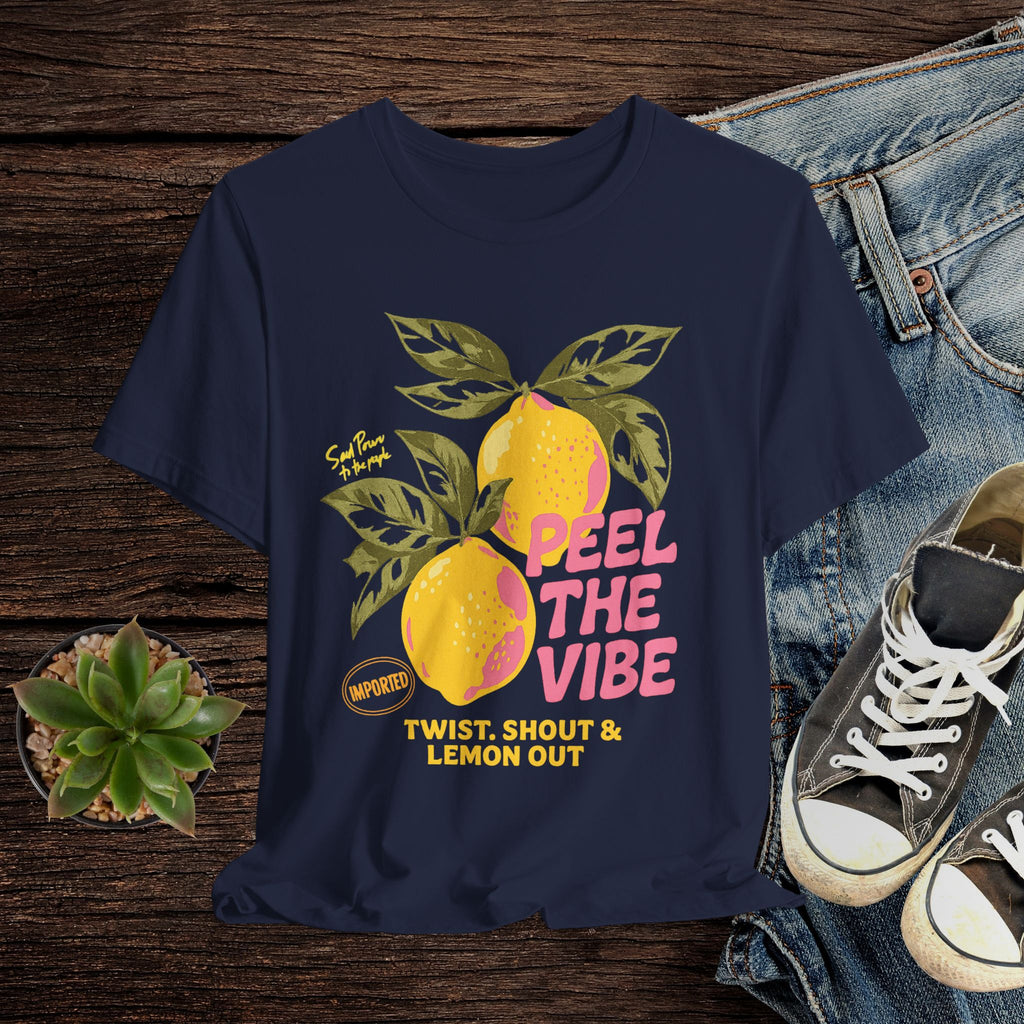 Navy blue t-shirt with lemon graphic and text on a wooden surface with jeans and sneakers.