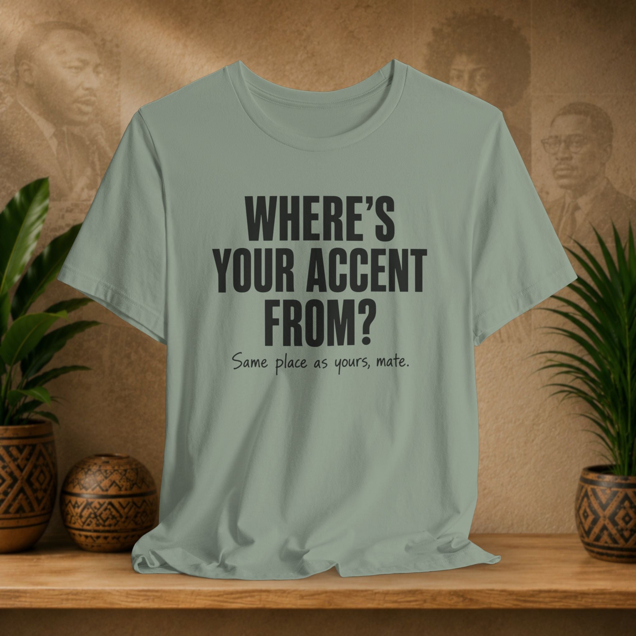 Light green t-shirt with text on a wooden surface with plants and a textured wall background