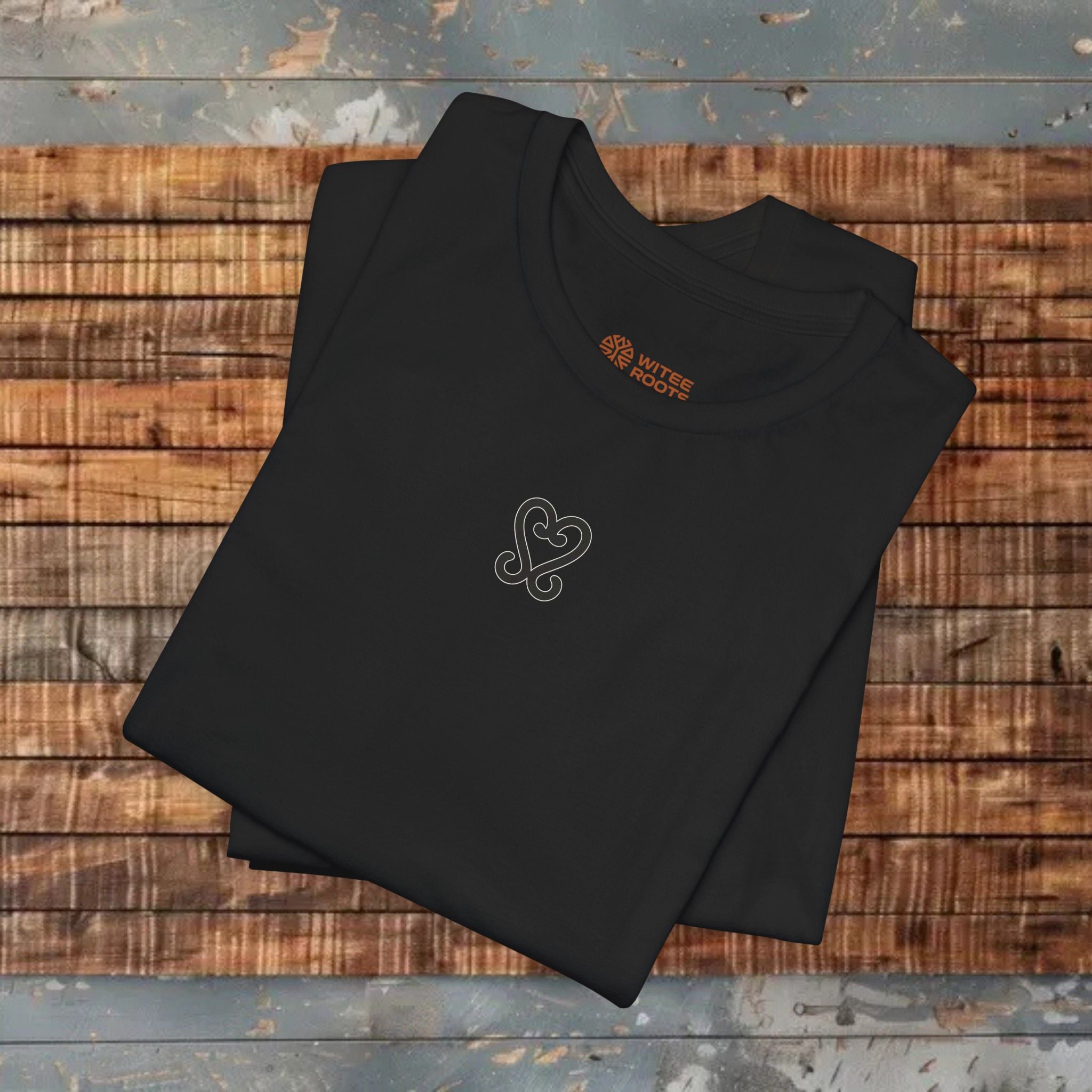 Folded black shirt with a logo on a wooden surface