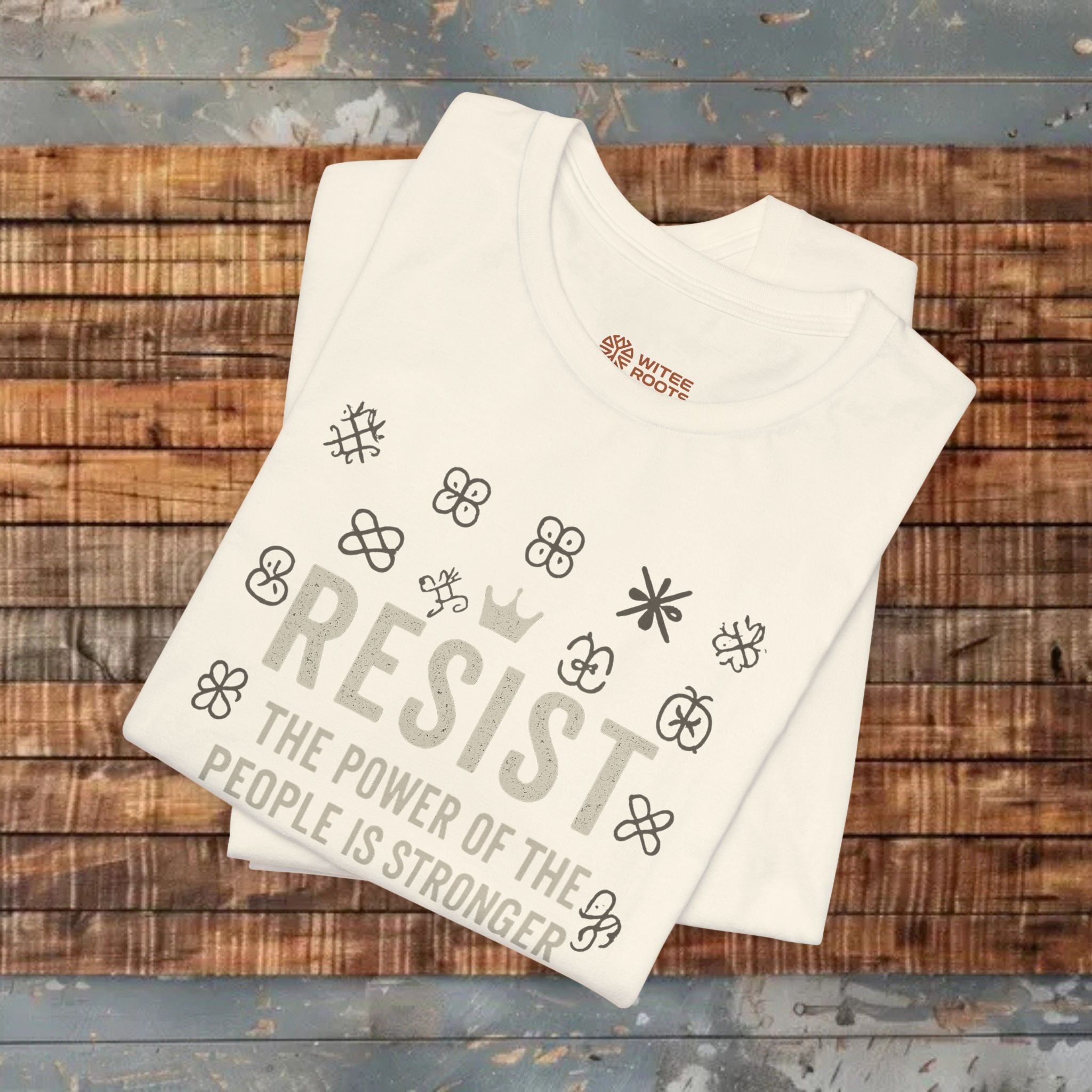 White t-shirt with printed text and graphics on a wooden surface