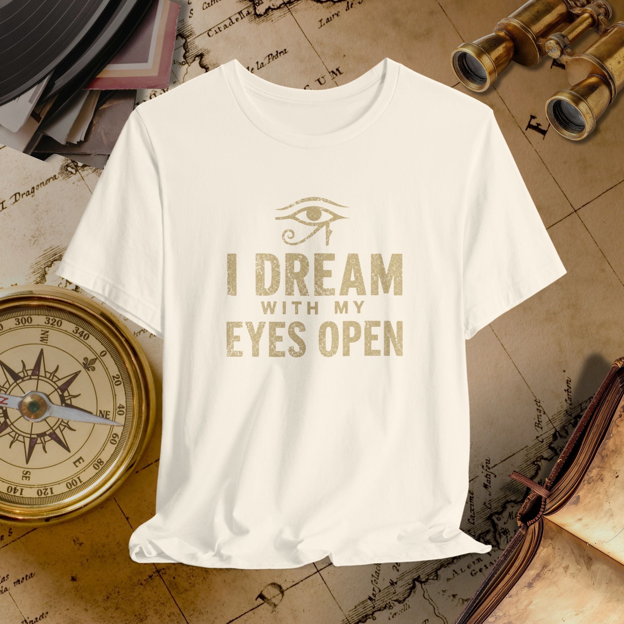 Beige t-shirt with 'I Dream with My Eyes Open' text and eye symbol on a vintage map background.