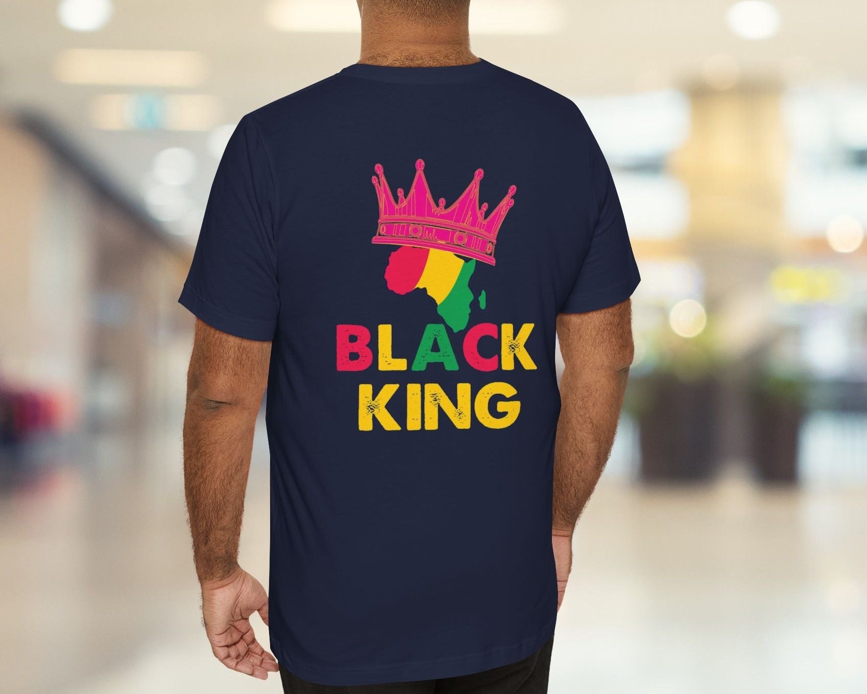 Person wearing a navy blue t-shirt with 'Black King' design in a mall.