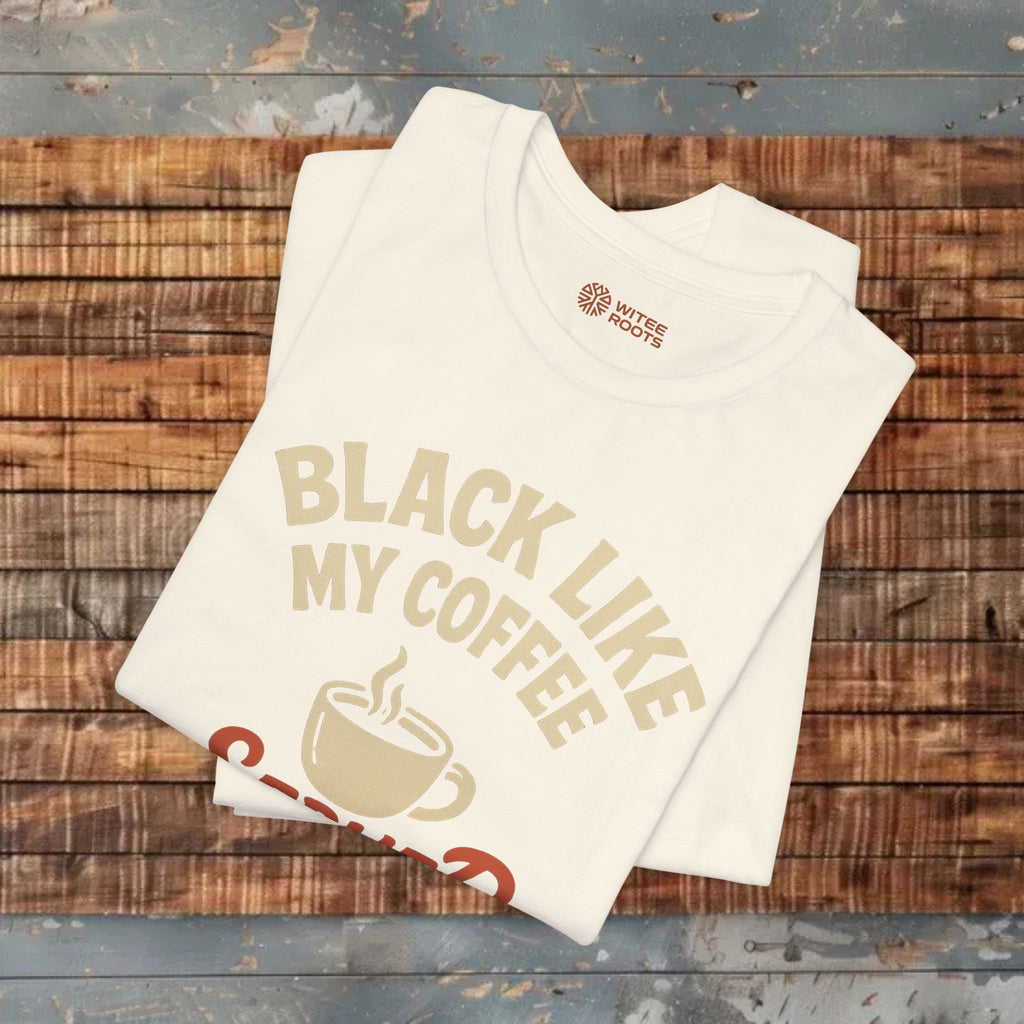 White t-shirt with 'Black Like My Coffee' text and coffee cup graphic on a wooden surface