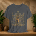 Gray t-shirt with a gold emblem design on a wooden surface with plants and decorative items.