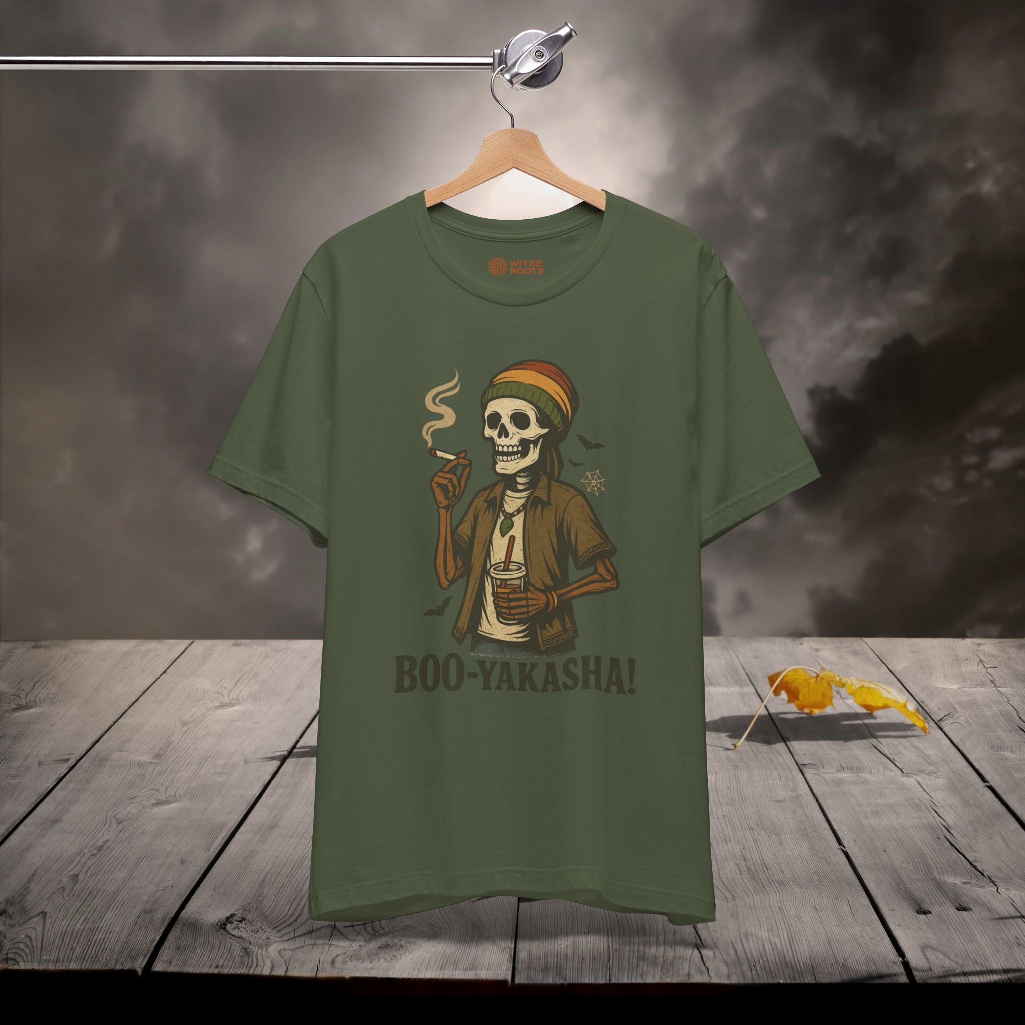 Green t-shirt with a skeleton design and 'BOO-YAKASHA!' text on a wooden surface with dark background