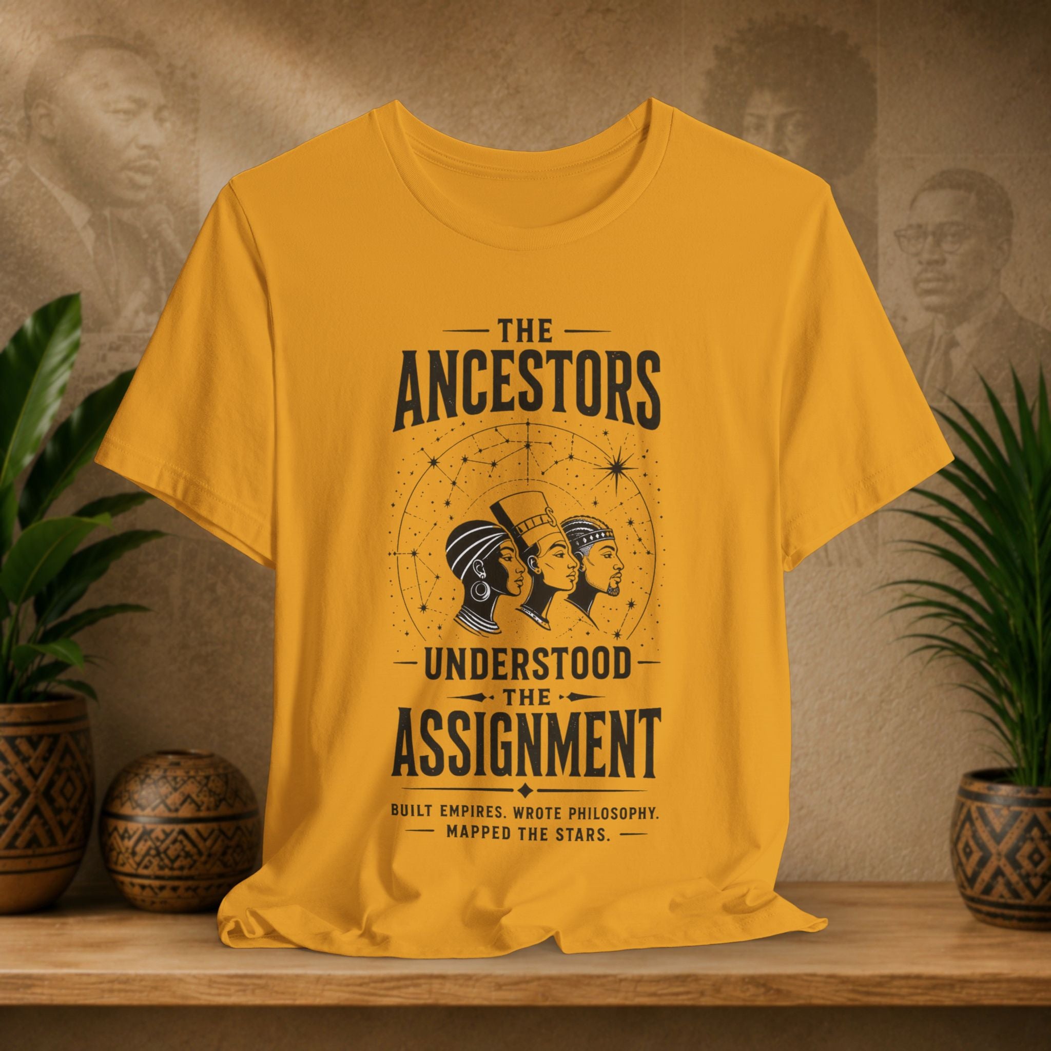 Yellow t-shirt with ancestors graphic on a wooden shelf with plants and decorative items.