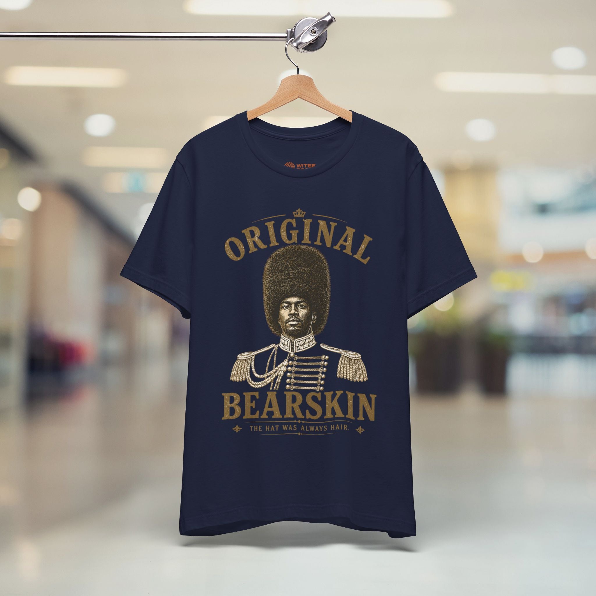 Navy blue t-shirt with gold graphic and text on a hanger in a store setting