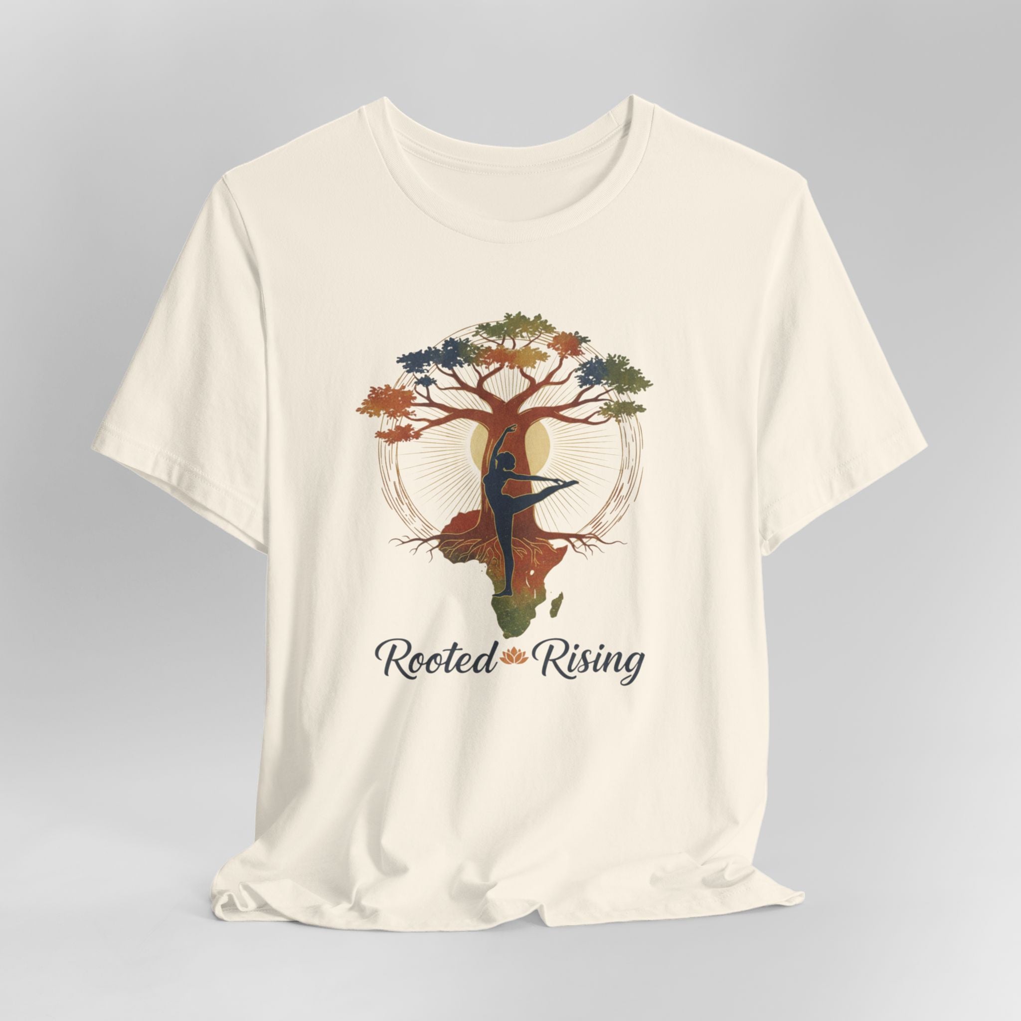 Beige t-shirt with a tree and dancer graphic and 'Rooted and Rising' text on a gray background
