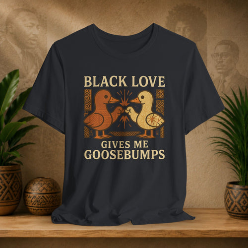 Black t-shirt with 'Black Love Gives Me Goosebumps' text and duck graphics on a wooden surface with plants.