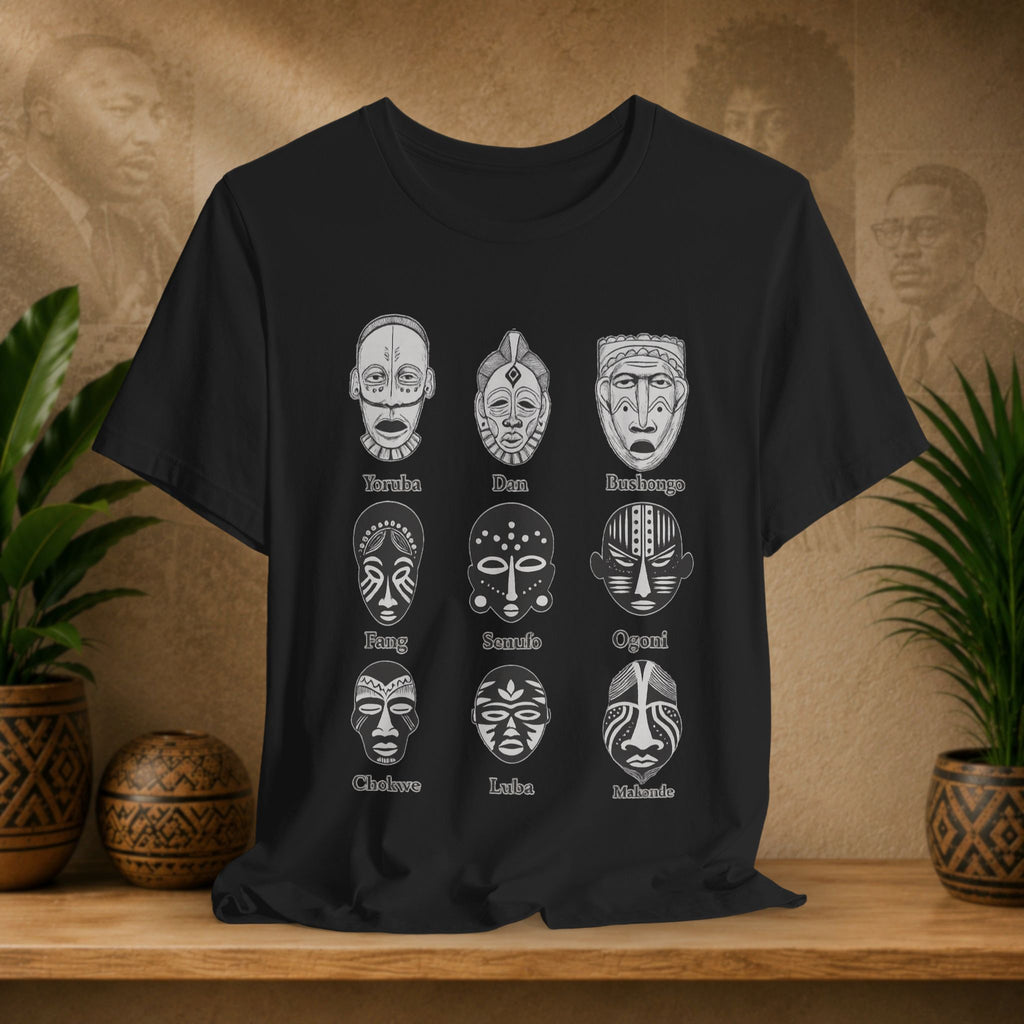 Black t-shirt with white mask designs on a wooden surface with plants and decorative items.