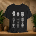 Black t-shirt with white mask designs on a wooden surface with plants and decorative items.