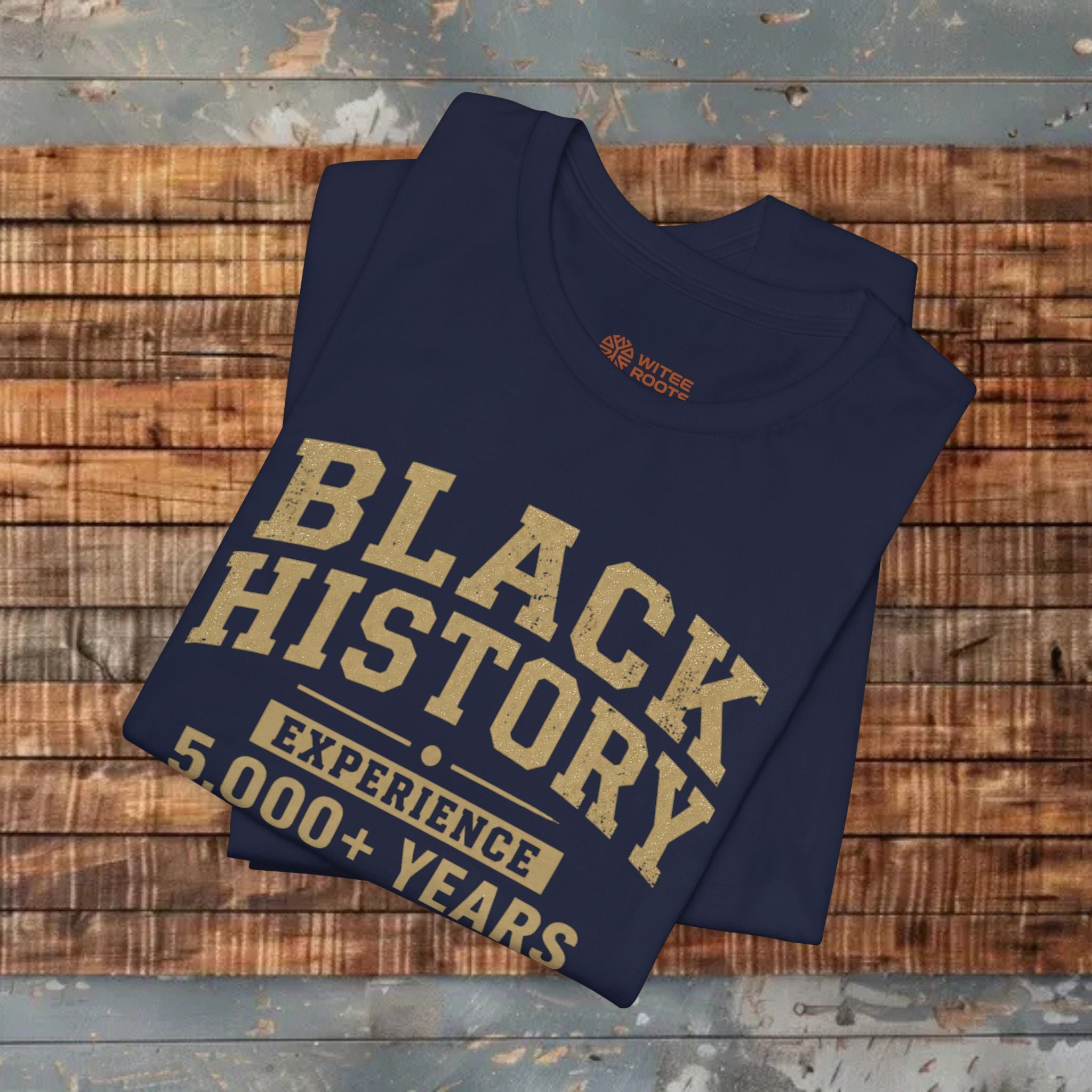 Folded navy blue t-shirt with 'Black History' text on a wooden surface