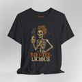 A black short-sleeve t-shirt with a graphic of a skeleton woman holding a beer, with the text 'BOO-TEE-LICIOUS' printed below in orange and beige. The shirt is displayed on a neutral gray background.