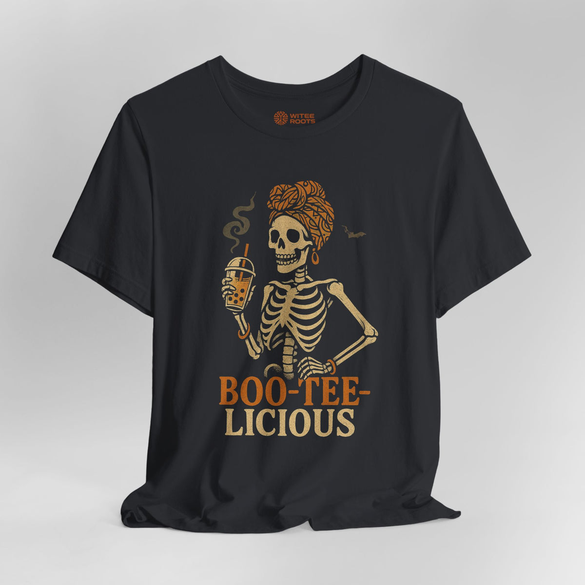 A black short-sleeve t-shirt with a graphic of a skeleton woman holding a beer, with the text 'BOO-TEE-LICIOUS' printed below in orange and beige. The shirt is displayed on a neutral gray background.