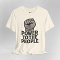 Beige t-shirt with a black fist graphic and 'Power to the People' text on a gray background